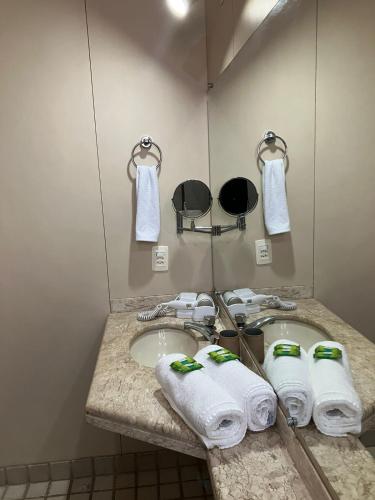 a bathroom with a sink with towels and a mirror at Apart Hotel Volpi 101 - Conforto & Comodidade in Belo Horizonte