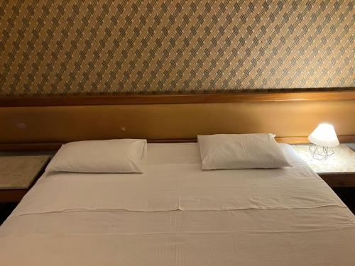 a bed with white sheets and pillows in a room at Apart Hotel Volpi 101 - Conforto & Comodidade in Belo Horizonte