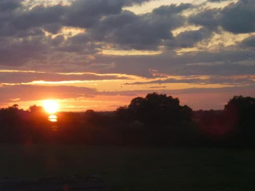 a sunset over a field with trees in the foreground at The Barn, Poplar Farm in York