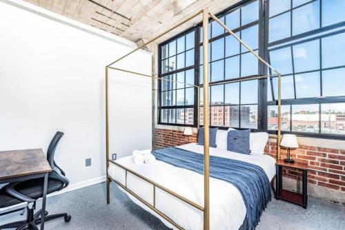 a bedroom with a bed and a desk and windows at STUNNING Architect loft by CozySuites in Saint Louis