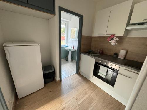 a small kitchen with a refrigerator and a sink at Au petit Meuh'ster in Munster