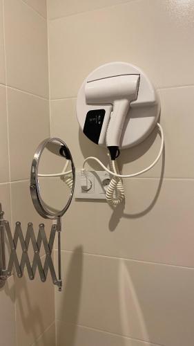 a white hair dryer and a mirror on a wall at Ouril Mindelo in Mindelo