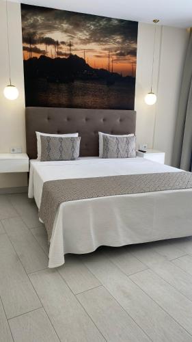 a bedroom with a large bed with a painting on the wall at Ouril Mindelo in Mindelo