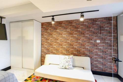 um sofá num quarto com uma parede de tijolos em Studio no Jabaquara a 2,8km da Expo imigrantes em São Paulo