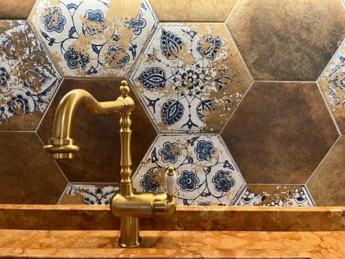een badkamer met een gouden kraan en blauwe en witte tegels bij Casa Luisa in Bardolino