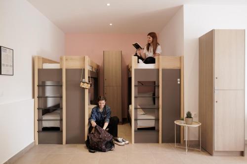 Local Hostel & Suites في مدينة كورفو: رجل وامرأة يجلسان على رأس أسرّة بطابقين