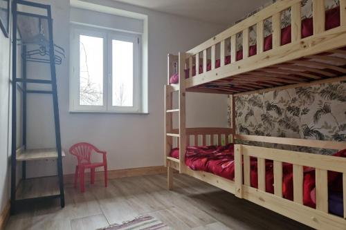 een slaapkamer met 2 stapelbedden en een rode stoel bij Chez la Mouzotte 