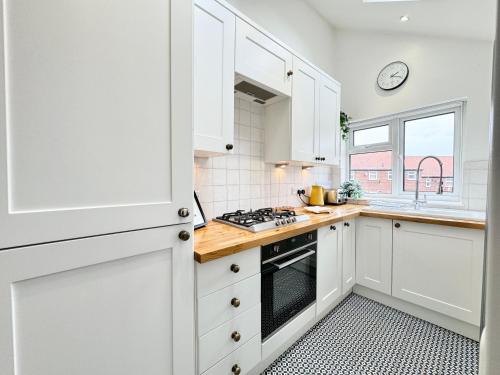 a kitchen with white cabinets and a stove top oven at Stylish and Cosy stay in the Heart of Malton in Malton