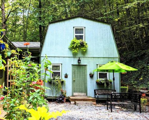 ein blaues Haus mit einer Bank und einem Regenschirm in der Unterkunft Hidden Hollow Bed and Breakfast in Otto