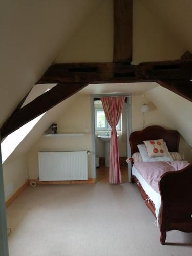 Cette chambre mansardée comprend un lit et une fenêtre. dans l'établissement Maison atypique semi-troglodyte, à Chinon