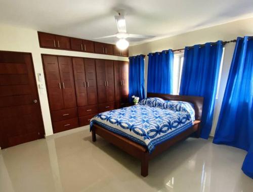 a bedroom with blue curtains and a bed in a room at Jarabacoa Villa Anchorage in Jarabacoa