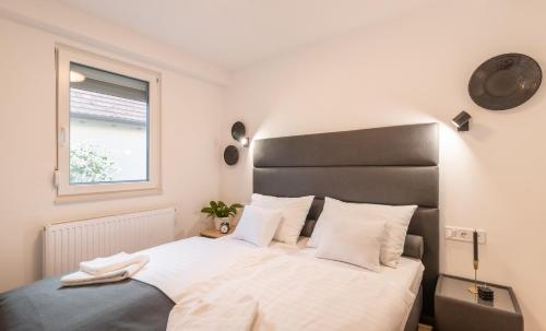 a bedroom with a bed with white sheets and a window at Ugo Apartman in Halászi