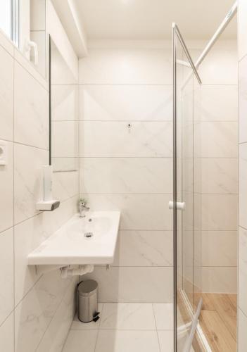 a white bathroom with a sink and a shower at Ugo Apartman in Halászi