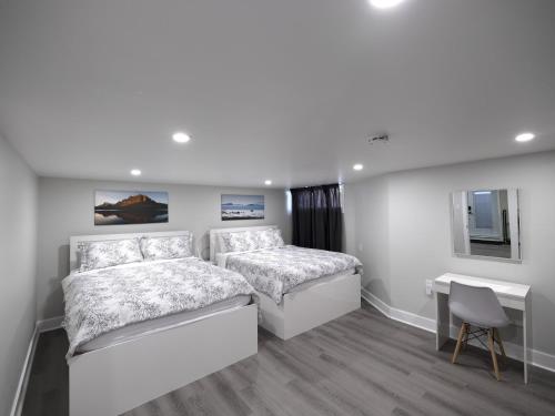 a white bedroom with two beds and a desk at Serene Niagara Guest House in Niagara Falls