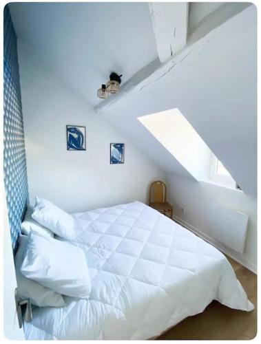 une chambre avec un lit blanc dans un grenier dans l'établissement Le flamboyant, à Angers