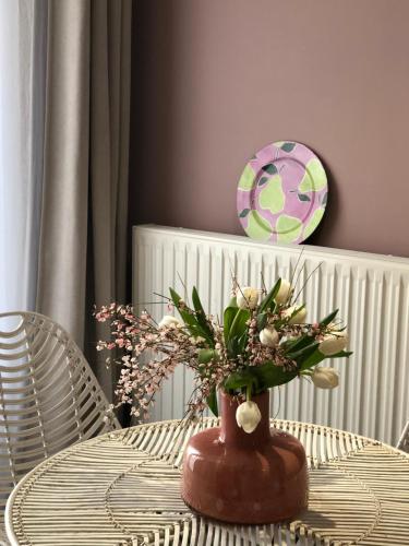 a table with a vase with flowers on it at Hotel Les Embruns in Le Touquet-Paris-Plage