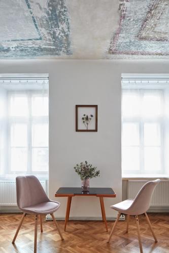 a table and two chairs in a room with windows at Stará Pekárna/Old Bakery in Znojmo