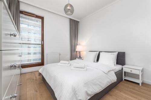 - une chambre blanche avec un grand lit et une fenêtre dans l'établissement Apartament Grzybowska 85 Premium by Your Freedom, à Varsovie