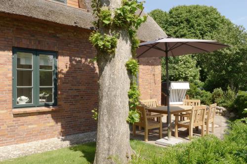 a table and chairs under an umbrella next to a brick building at Altes Museum Haus 2 in Oevenum
