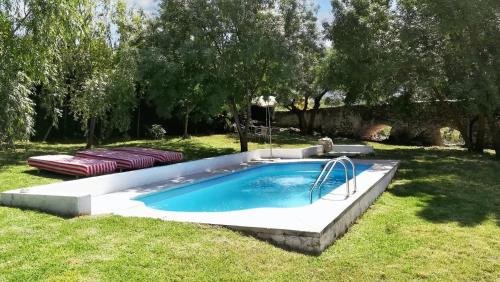 uma piscina na relva com duas camas em 6 bedrooms villa with private pool enclosed garden and wifi at Villanueva del Trabuco em Villanueva del Trabuco