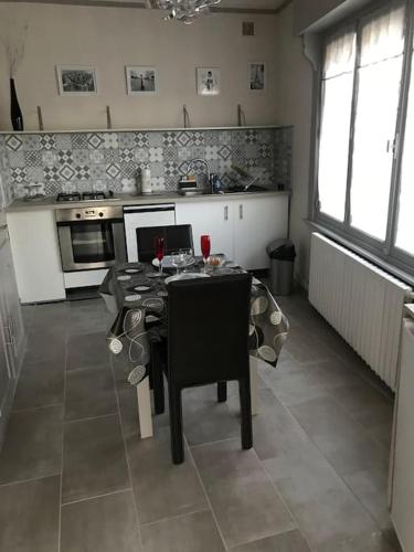 une cuisine avec une table et des chaises et une cuisine avec une cuisinière dans l'établissement MAISON AVEC JACUZZI PRIVATIF, à Cambrai