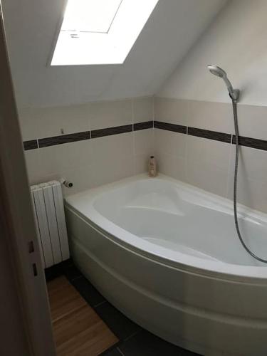 La salle de bains est pourvue d'une baignoire et d'une douche. dans l'établissement MAISON AVEC JACUZZI PRIVATIF, à Cambrai