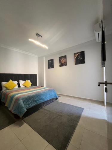 - une chambre avec un lit doté d'oreillers jaunes et une télévision dans l'établissement Appartement aéroport Marrakech, à Marrakech