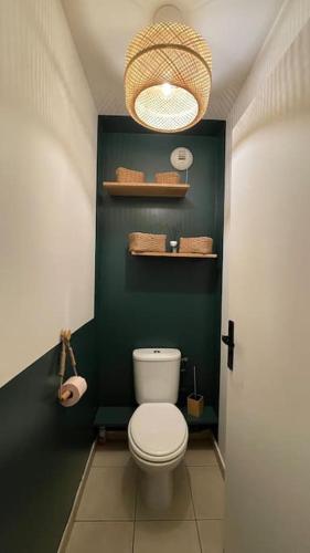 La salle de bains est pourvue de toilettes blanches et d'un mur vert. dans l'établissement Appartement entier Paris/Disney, à Champs-sur-Marne