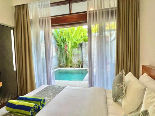 a bedroom with a bed and a view of a pool at Livin Sanur Villa in Denpasar