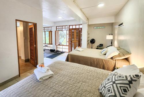 a bedroom with two beds and a hallway with windows at Tropical Paradise, Oceanfront Home in the Jungle in Bocas del Toro