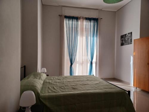 1 dormitorio con 1 cama y una ventana con cortinas azules en Jolie, en Castellammare di Stabia