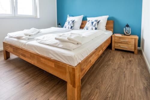 a large wooden bed with white sheets and pillows at Hangar 19 Luxusbungalow am See H8 in Schwerin
