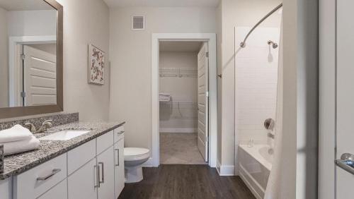 a white bathroom with a toilet and a sink and a tub at Landing at eXchange - 2 Bedrooms in Downtown Detroit in Detroit