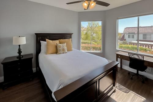 a bedroom with a bed and a desk and two windows at Encantamar Escape in Dana Point
