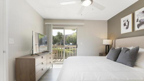 een witte slaapkamer met een bed en een televisie bij Landing at Bartram Park - 3 Bedrooms in Southside in Jacksonville