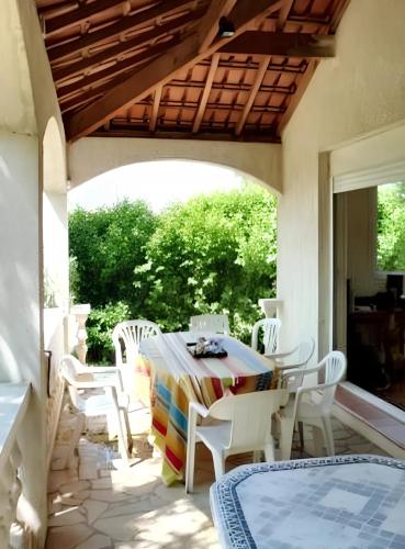 d'une terrasse avec une table et des chaises blanches. dans l'établissement Villa spacieuse à Aimargues avec piscine privée, à Aimargues