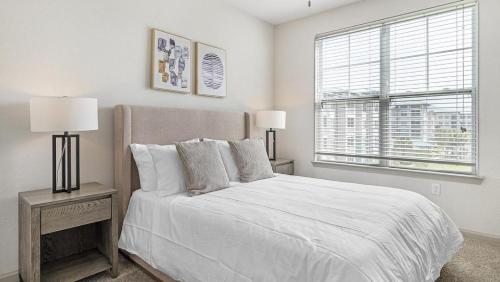 a bedroom with a bed with two lamps and a window at Landing at Three Rivers - 1 Bedroom in Central Fort Wayne in Fort Wayne