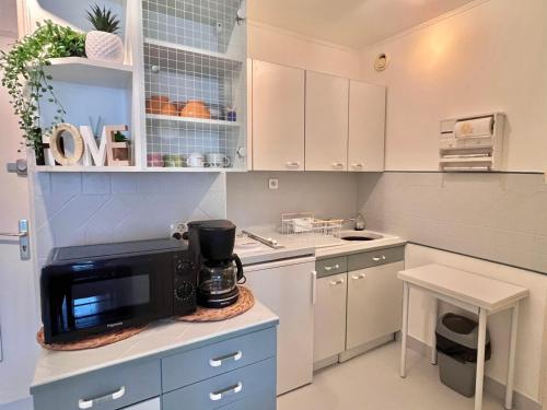 une cuisine avec des placards blancs et un four micro-ondes sur un comptoir dans l'établissement Studio Cabine avec Parking Privatif, Climatisation et TV à La Grande-Motte - FR-1-716-21, à La Grande Motte