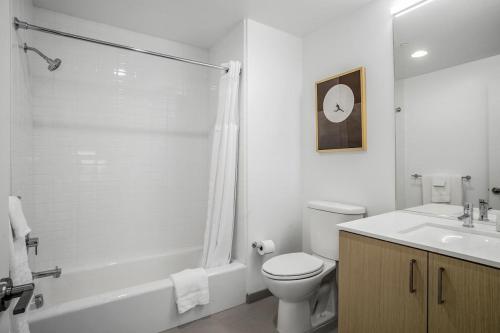 a white bathroom with a toilet and a sink at Landing at Logan Apartments - Studio in Logan Square in Chicago