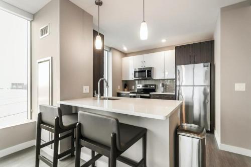 a kitchen with a counter with chairs and a refrigerator at Landing at Logan Apartments - Studio in Logan Square in Chicago