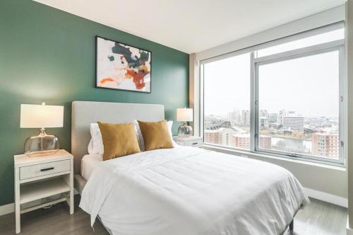 a bedroom with a white bed and a large window at Landing at Logan Apartments - Studio in Logan Square in Chicago