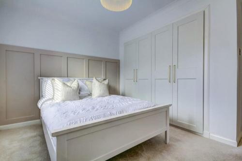 a white bedroom with a large bed with white cabinets at Shawfarm - Open Championship 24 in Monkton