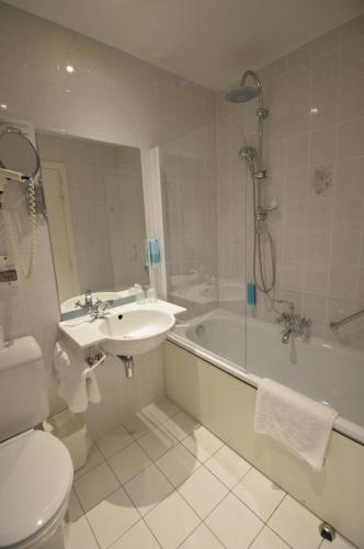 a bathroom with a sink and a tub and a toilet at Hotel de la Poste - Relais de Napoleon III in Bouillon