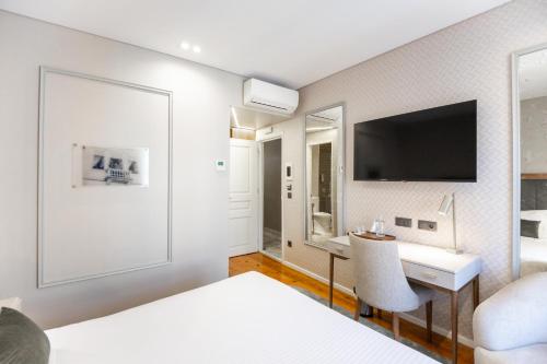 a bedroom with a bed and a desk and a tv at Avenida Boutique Hotel in Viseu