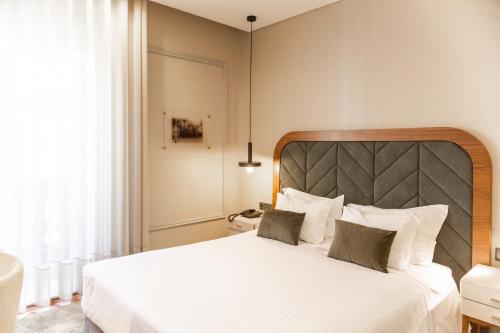 a bedroom with a large white bed with two pillows at Avenida Boutique Hotel in Viseu