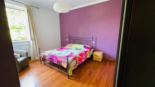 a bedroom with a bed and a purple wall at Casa Bella Vista in Gubbio