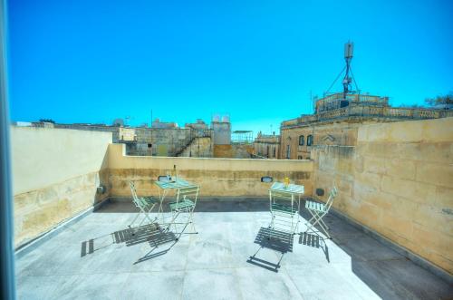 a balcony with chairs and tables on a building at Cozy 1bedroom, roof terrace near Valletta DAZZ1-2 in Il-Furjana