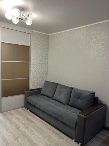 a living room with a gray couch in a room at 2 комнатная за Хан шатыром левый берег in Taldykolʼ
