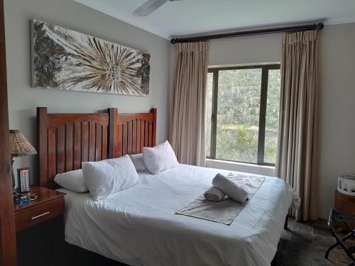 a bedroom with a white bed with a towel on it at African Safari Lodge in Grahamstown