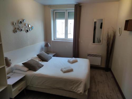 a bedroom with a white bed and a window at Hôtel Le P'tit Monde in Montignac